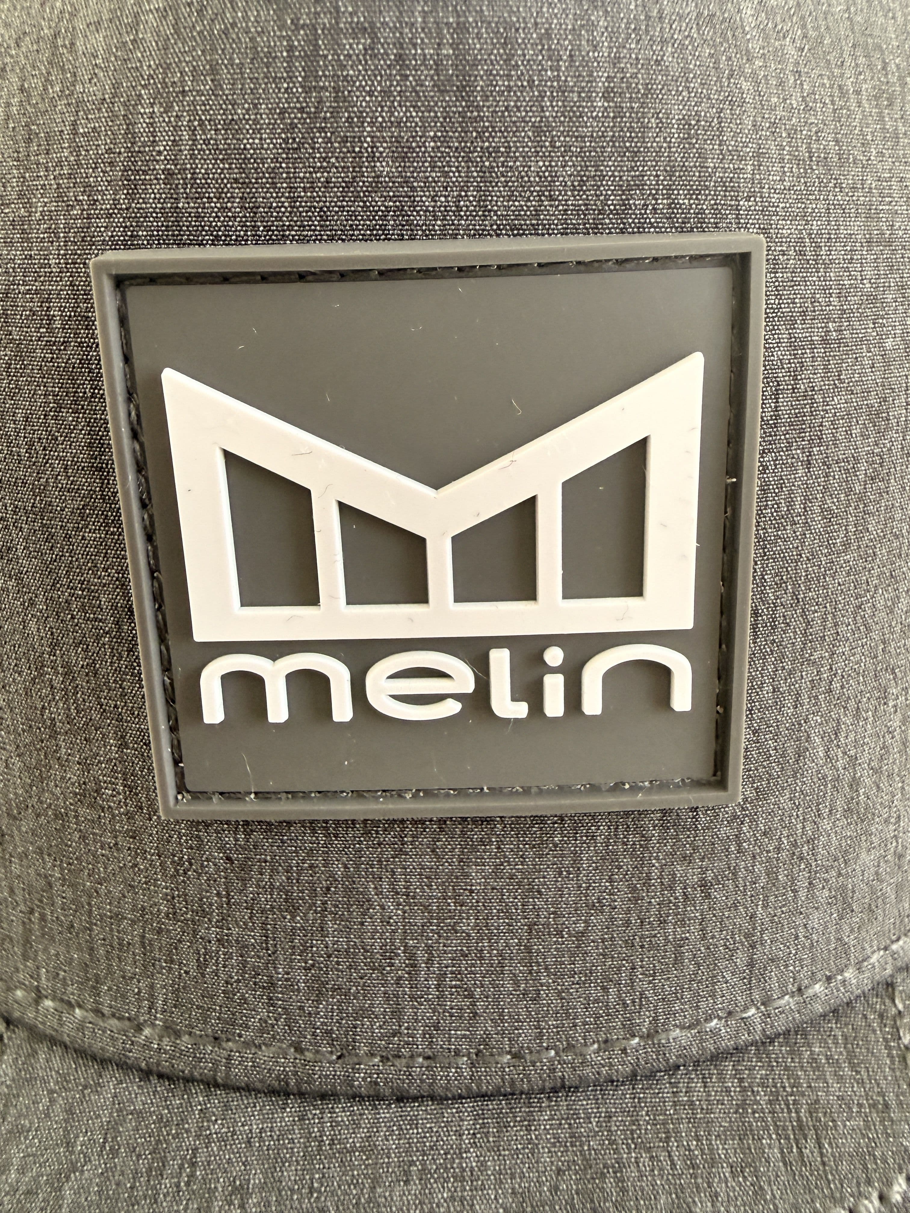 Close-up of the rubber Melin logo patch on the front panel of the Odysea Stacked HYDRO