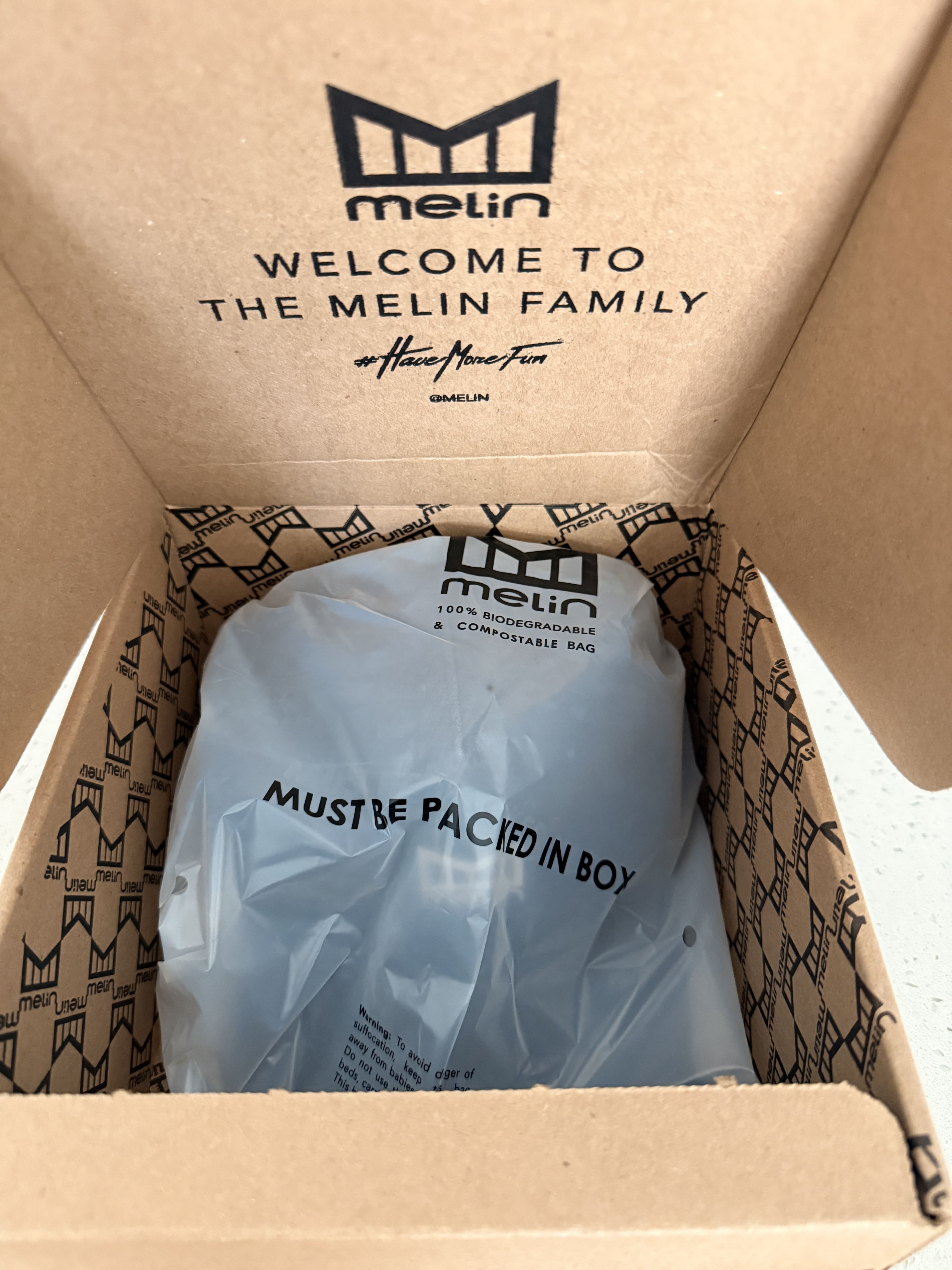 Interior of the Melin shipping box reading "Welcome to the Melin Family," with the hat sealed in a biodegradable poly bag