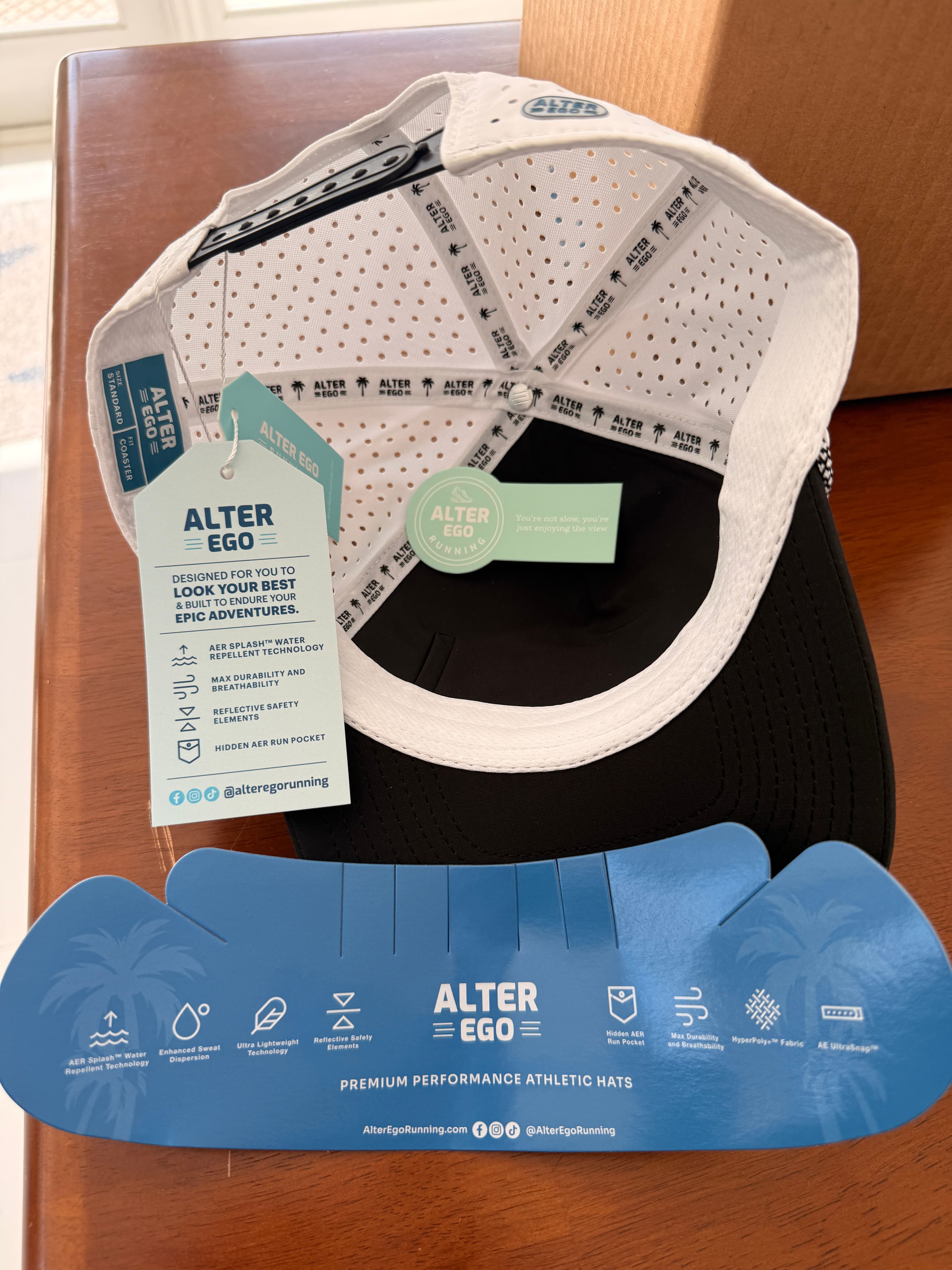 Interior of the Alter Ego Coaster Splash Classic Black White Palm hat showing the perforated lining, sweatband, and printed feature tags