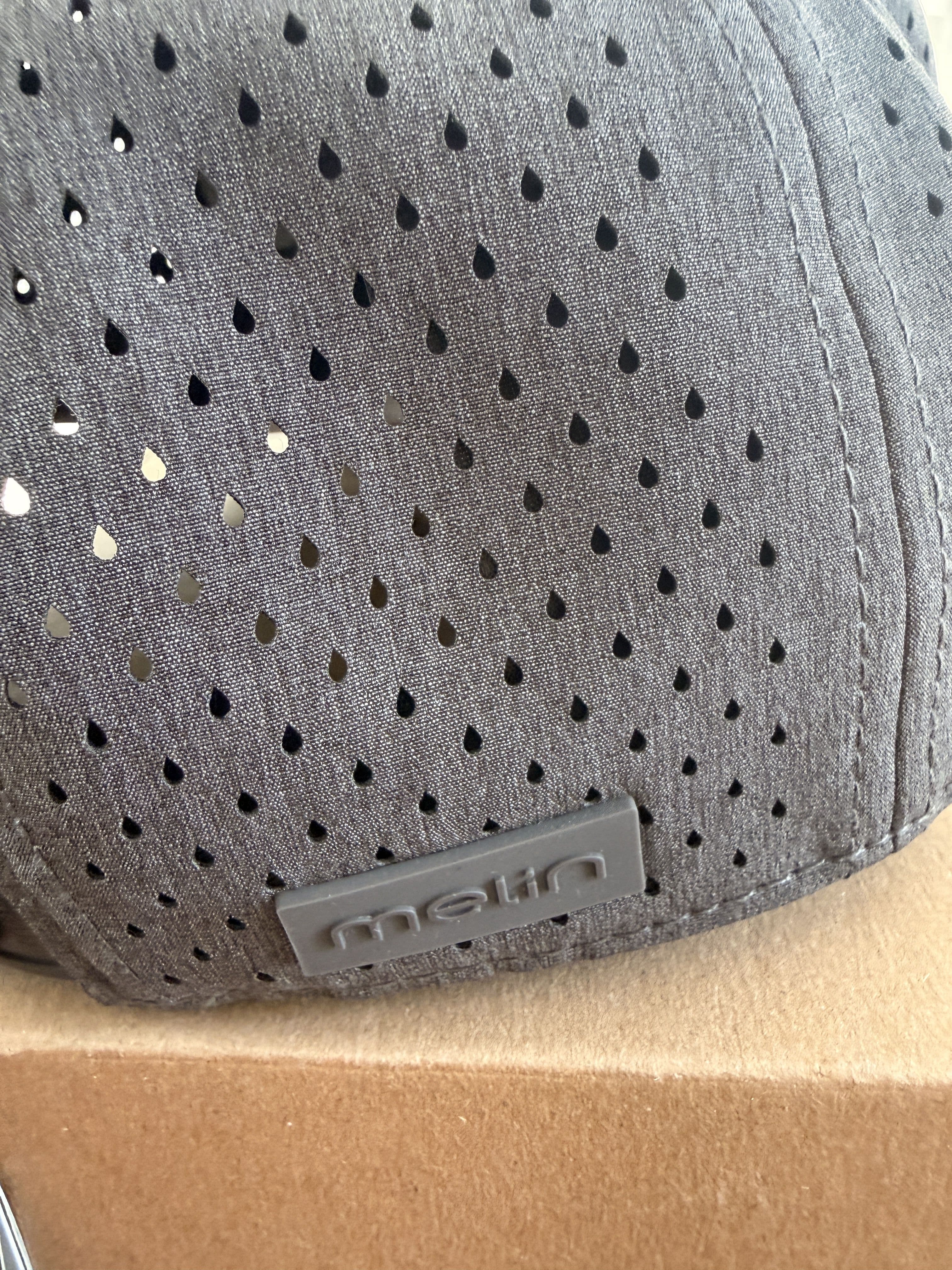 Close-up of the raindrop-shaped laser perforations and side Melin tab on the crown