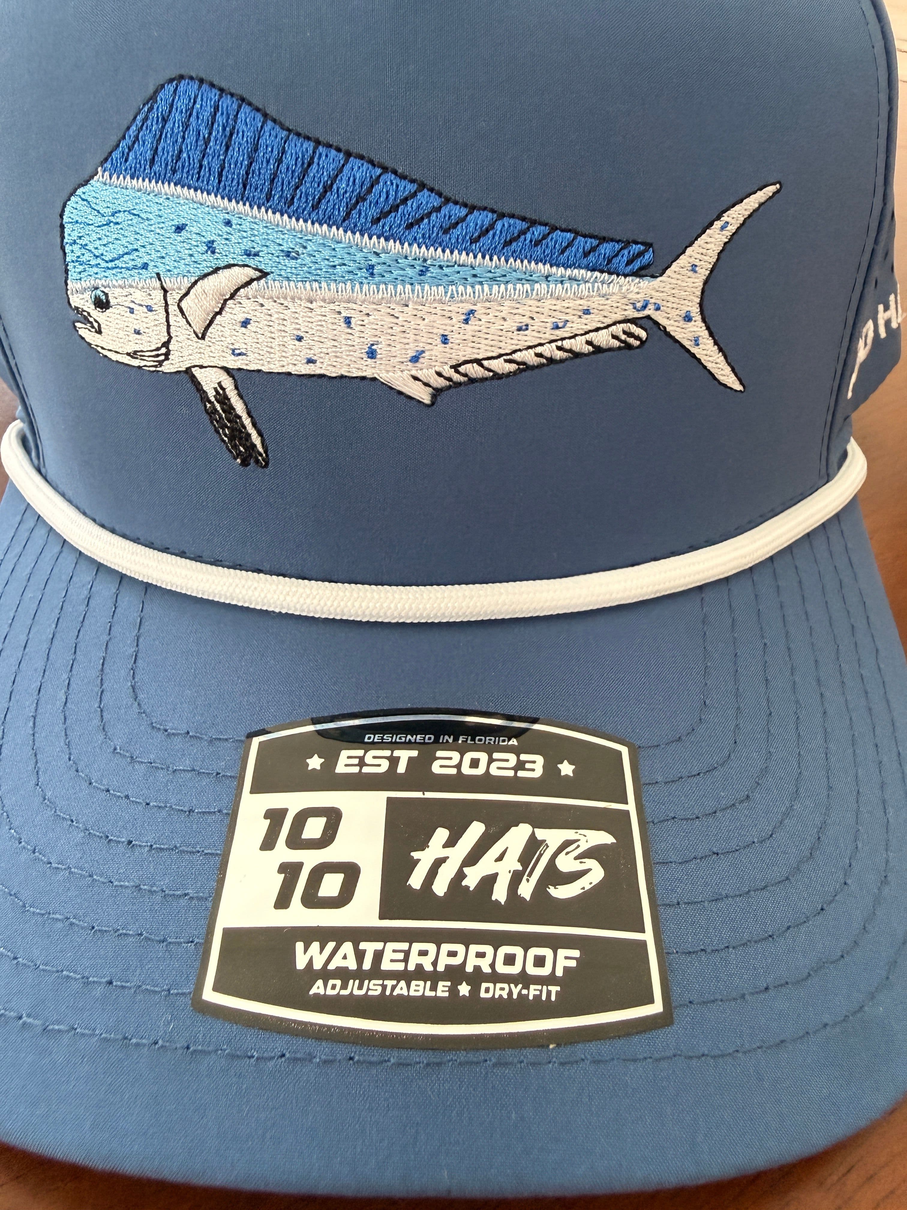 Close-up of the embroidered mahi-mahi design and white rope trim on the 10-10 Hats Mahi Fish Hat, with the woven brim tag visible